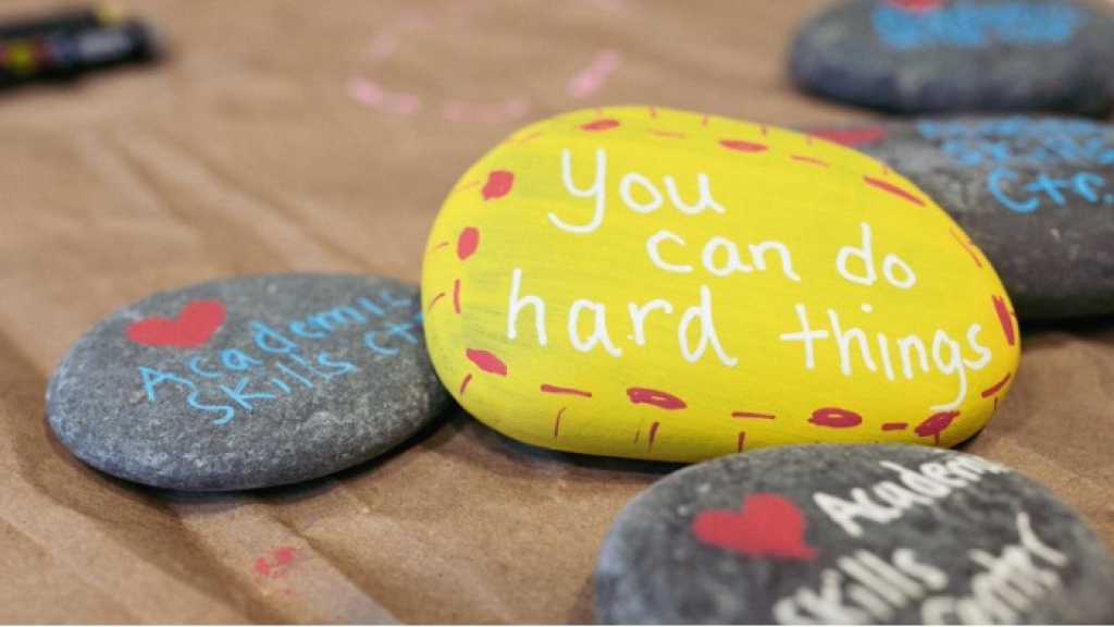 Rocks with motivational sayings on them sit on a desk.