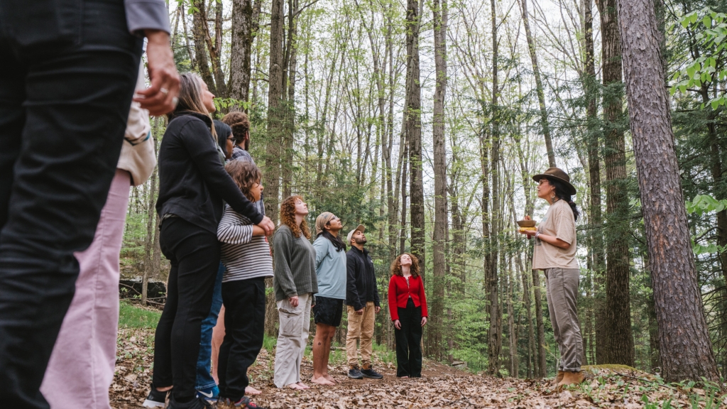 Belinda Chiu ’98, a member of the Mindful Dartmouth Initiative planning team, leads a group of students, faculty, and staff through a wooded area around Dartmouth as part of a forest bathing experience. She holds a chime in her hand to signal when a meditation begins and ends. 